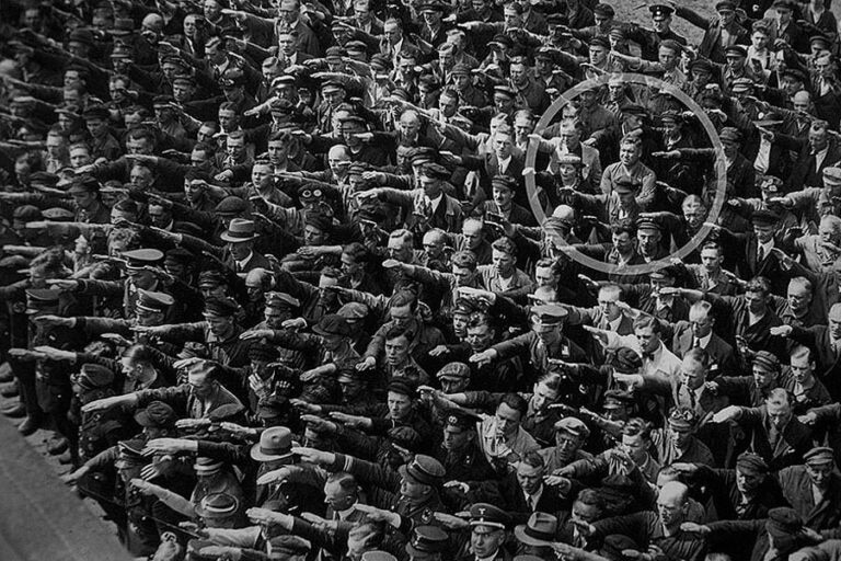 Abbildung einer Menge, die den Hitlergruß zeigt. Unter ihnen befindet sich ein mutiger Mann, der dies verweigert.