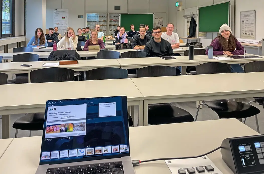 Hörsaal mit 18 Studenten des Bauingenieurwesens, darunter 6 weibliche Studenten, bei meiner Vorlesung Sprengtechnik am KIT im Oktober 2023. Im Vordergrund ist der Laptop mit dem Foliensatz der Vorlesung zu sehen, in der ich auch Gendern 2.0 vorstelle.